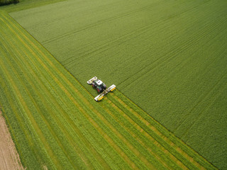 Aerial view of a tractor mowing a green fresh grass field, 
a farmer in a modern tractor mowing a...