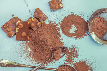 cocoa powder and chocolate pieces on a light blue background