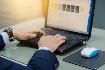 Close up of business person's hands using laptop on table in the office. Close shot of office workers using laptop in the office.