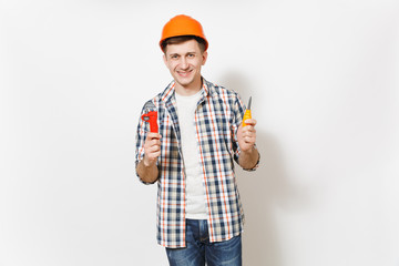 Young smiling handsome man in protective orange hardhat holding toy screwdriver and adjustable wrench isolated on white background. Instruments for renovation apartment room. Repair home concept.