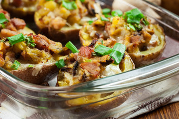 Baked potatoes in jacket stuffed with bacon, mushrooms and cheese. Dish served in baking dish..Baked potatoes stuffed with bacon, mushrooms and cheese