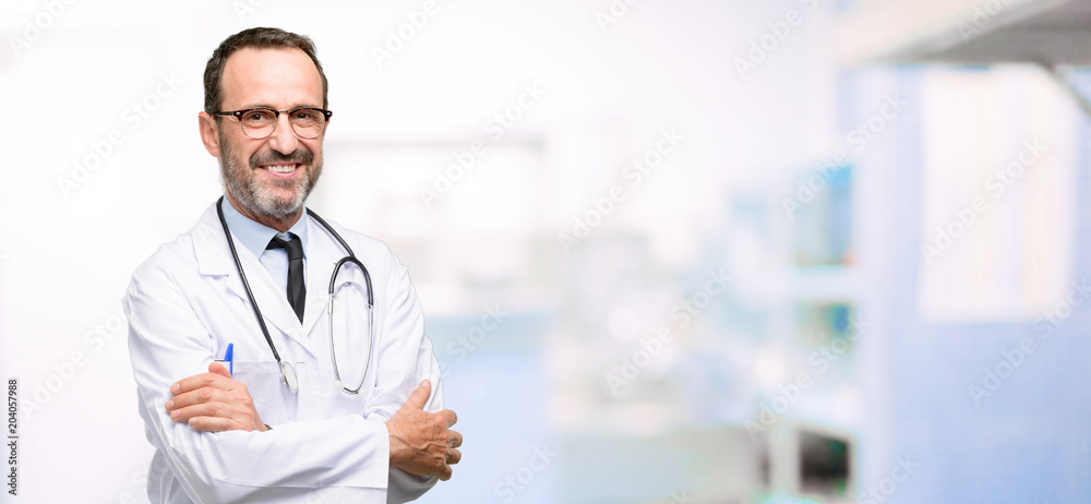 Wall mural doctor senior man, medical professional with crossed arms confident and happy with a big natural smi