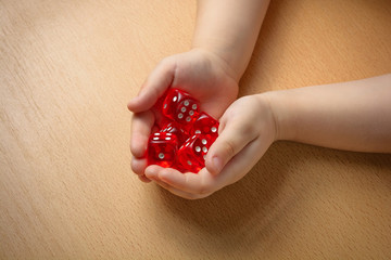 The child holds the dice in his hands for a family board game. Concept of luck, game, gamble,...