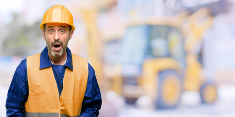 Senior engineer man, construction worker scared in shock, expressing panic and fear at work