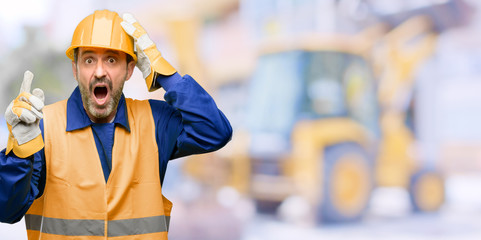 Senior engineer man, construction worker pointing away side with finger at work - obrazy, fototapety, plakaty