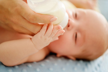 Fototapeta na wymiar Nursing a baby. Feeding the newborn with formula in a bottle. Breastfeeding problems. Mother’s love and warmth.