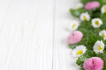 White and pink flowers are a white wooden table.