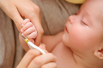 Baby getting fingernails cut while sleeping by his mother with scissors. Nursing a child. How to...