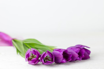 A bunch of purple tulips on a white wooden table.