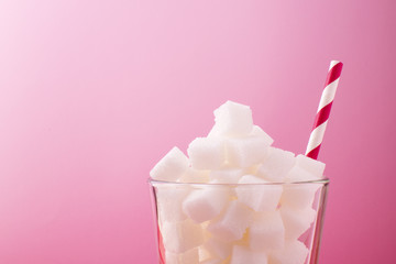 sugar in a glass on a pink background, side view
