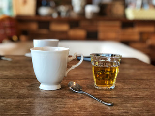 Black coffee on beautiful white cup and hot tea glass , stainless spoon on the vintage wooden table, Relaxing in Cafe.