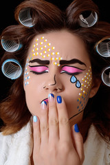 Model with pop art makeup against black background.