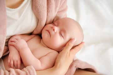 Mother holding small sleeping child in her arms. Baby love concept. Tenderness and care. Nursing infants