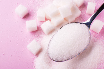 spoon with sugar close-up on a pink background