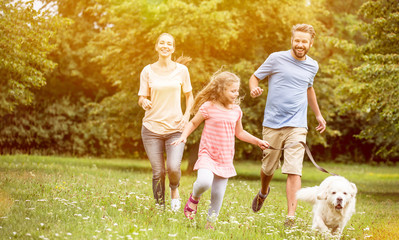 Obraz premium Familie mit Tochter und Hund spielen im Garten