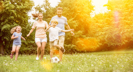 Familie und Kinder spielen Fußball im Garten