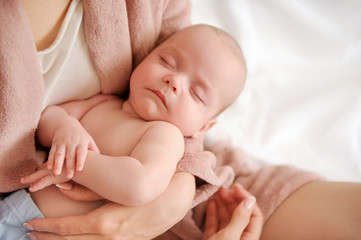Mother holding small sleeping child in her arms. Baby love concept. Tenderness and care. Nursing infants