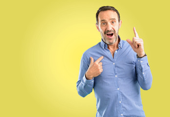 Handsome middle age man happy and surprised cheering expressing wow gesture pointing up