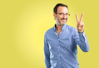 Handsome middle age man raising his fingers, number two