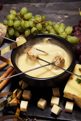 Gourmet Swiss fondue dinner on a winter evening with assorted cheeses on a board alongside a heated pot of cheese fondue