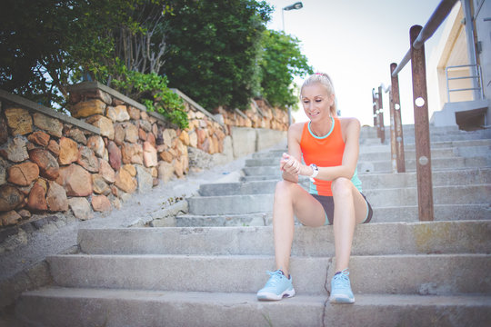 Blond female fitness model resting on some stairs during her exercise