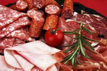 Food tray with delicious salami, ham,  fresh sausages and herbs. Meat platter with selection