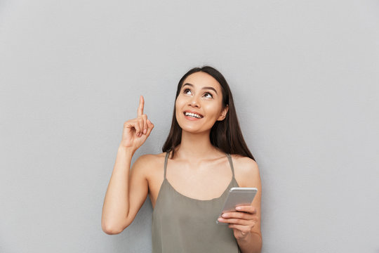 Portrait of an excited asian woman holding mobile phone