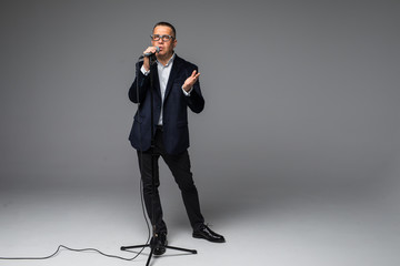 Portrait of a happy mature man presented with microphone or singing isolated full body on white...