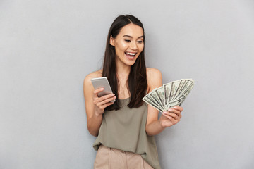 Portrait of a cheerful asian woman holding money banknotes