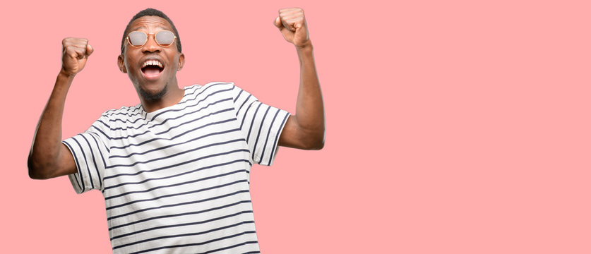 African Black Man Wearing Sunglasses Happy And Excited Celebrating Victory Expressing Big Success, Power, Energy And Positive Emotions. Celebrates New Job Joyful