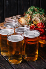 Five glasses of beer near the set of grilled meat. Party concept