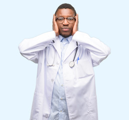 Young black doctor, medical professional covering ears ignoring annoying loud noise, plugs ears to avoid hearing sound. Noisy music is a problem.