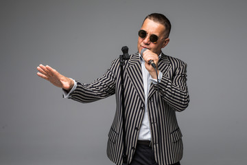 The mid age Showman interviewer with emotions. Young elegant mature man holding microphone against white background. Showman concept.