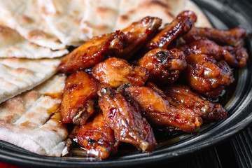 Juicy fried chicken wings with flatbread and on wood backiground