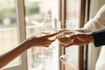 Young happy friends cheering with glasses of white wine, group of people celebrating anniversary at home, cozy atmosphere, family dinning at restaurant, togetherness and traditional concept