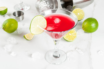 Red cosmopolitan cocktail with lime in martini glass, on white marble background copy space - obrazy, fototapety, plakaty