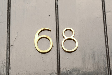 House number 68 sign on black painted wooden door