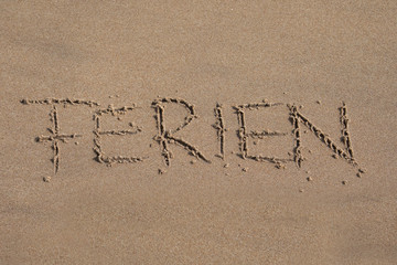  Das Wort Ferien in den Sand geschrieben