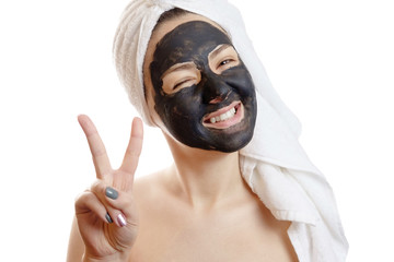  close-up portrait beautiful woman with facial black mask on white background, girl with a white towel on her head, satisfied and happy