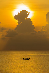 Fishing boat silhouette and ripples of sea water during sunrise in Thailand