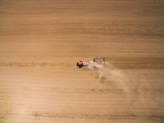 aerial view - a modern tractor working on the agricultural field - tractor plowing and sowing in the agricultural field - high top view