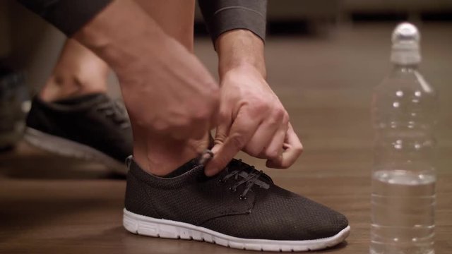 Man tying his sports shoe at gym