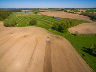 Fototapeta na wymiar aerial view - a modern tractor working on the agricultural field - tractor plowing and sowing in the agricultural field - high top view