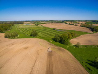 Obraz premium aerial view - a modern tractor working on the agricultural field - tractor plowing and sowing in the agricultural field - high top view