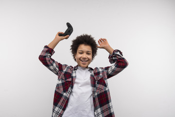 Game player. Happy cheerful boy smiling to you while enjoying his victory