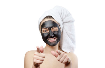  close-up portrait beautiful woman with facial black mask on white background, girl with a white towel on her head, satisfied and happy  smile, pointing hands at the camera