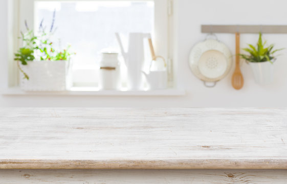 Wooden table top over blurred kitchen interior with copy space
