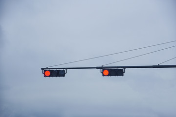 A stop signal was turned on at the traffic light with a cloudy sky background.
