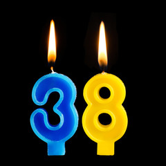 Burning birthday candles in the form of 38 thirty eight for cake isolated on black background.