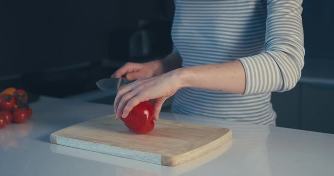 Young woman cutting a red pepper